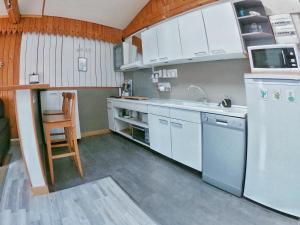 a kitchen with white cabinets and a white refrigerator at La Caravelle - Chalet t2 climatisé lit queen size ou twin in Tarbes