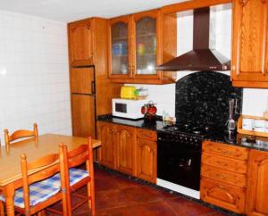 a kitchen with wooden cabinets and a black stove top oven at Casa bartolin in Gédrez