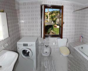 biała łazienka z umywalką i pralką w obiekcie Casa bartolin w mieście Gédrez