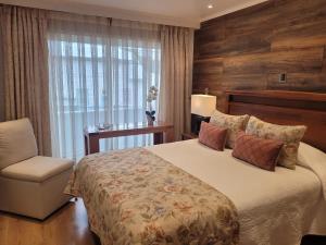 a bedroom with a bed and a chair and a window at Hotel Puerta del Lago in Puerto Varas