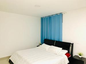 1 dormitorio con cama blanca y cortinas azules en Apartahotel Bahia Tropical II, en San Andrés