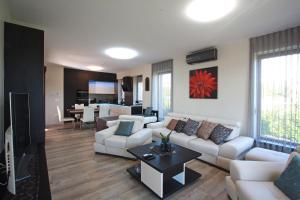 uma sala de estar com sofás brancos e uma cozinha em Paloznak Lux Apartmanház em Paloznak