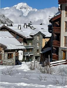 a snow covered building with a mountain in the background at Le Refuge du Montagnard, Arc 1950, Skis aux pieds, Spa in Arc 1950