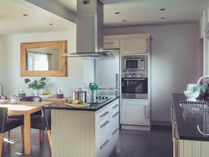 uma cozinha com armários brancos e um forno com placa de fogão em Craster Reach em Alnwick