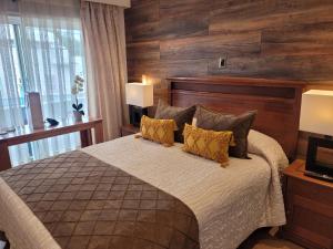 1 dormitorio con 1 cama grande y paredes de madera en Hotel Puerta del Lago, en Puerto Varas