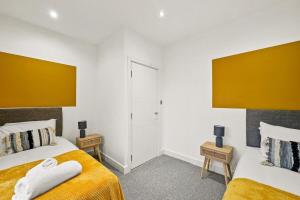 two beds in a bedroom with yellow and white at April Disc - Long Stay - Contractors in Swindon