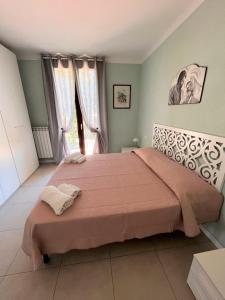 Schlafzimmer mit einem großen Bett mit rosa Bettwäsche und Fenstern in der Unterkunft TRILO COPPO CON SPIAGGIA E POSTO AUTO in Numana