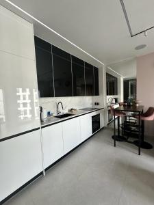 a kitchen with white cabinets and a wooden table at TheOne - Apartament Księcia Witolda in Wrocław