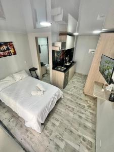 a bedroom with a white bed and a bathroom at Las Aguas Social Experience in Bogotá