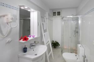 La salle de bains blanche est pourvue d'un lavabo et d'une douche. dans l'établissement Sea View Studios, à Finikas