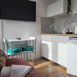 a kitchen with white cabinets and a table and a counter at Apartamenty Ustroń Wczasowa 90 in Ustroń