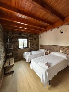 a bedroom with two beds and a stone wall at A Barreira in Ferrol
