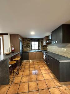 a large kitchen with black cabinets and a tile floor at A Barreira in Ferrol