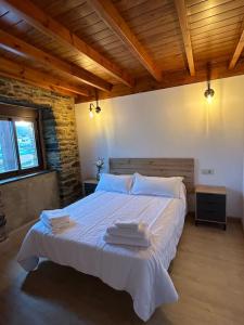 a bedroom with a white bed with towels on it at A Barreira in Ferrol