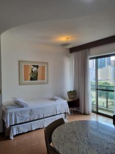 a hotel room with a bed and a large window at Flat Pancetti in Belo Horizonte