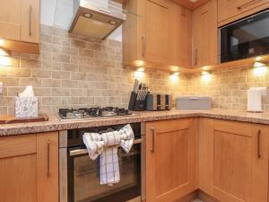a kitchen with wooden cabinets and a stove top oven at 10 Haw Grove in Skipton