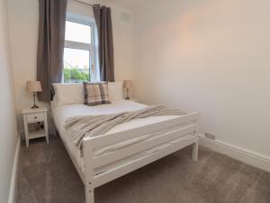a white bed in a room with a window at 10 Haw Grove in Skipton