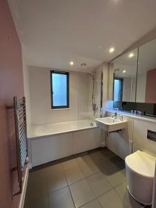 a bathroom with a tub and a toilet and a sink at Stay in Style: Modern 2-Bed In Trendy London Area in London