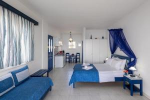 a bedroom with a blue and white bed and a kitchen at Sea View Studios in Finikas