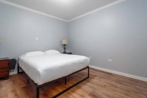 Posto letto in camera con pareti bianche e pavimenti in legno. di MTM Fully Furnished Rental in Old Town - 2 Beds a Chicago