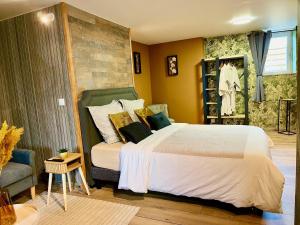 1 dormitorio con 1 cama blanca, 1 silla y 1 sofá en Le Manoir des Haies en Les Champs-Géraux