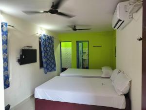 a bedroom with two beds and a ceiling fan at Arputha Lodge in Nāgappattinam +10 photos