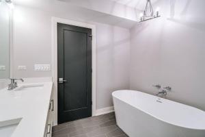 ein weißes Bad mit einer Badewanne und einer schwarzen Tür in der Unterkunft Immaculate Brand New Condo Downtown in Chicago