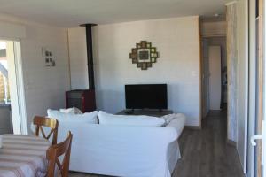 a living room with a white couch and a tv at L'annexe de la Villa Darom, Andernos les bains. in Andernos-les-Bains