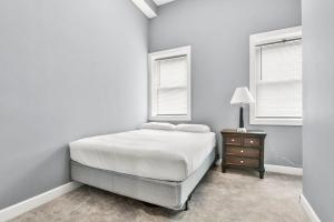 a white bedroom with a bed and a nightstand and two windows at Lovely 2-Bedroom Unit in Springfriend in Springfield
