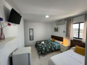 a hotel room with two beds and a tv at Hostal Avenida in Conil de la Frontera