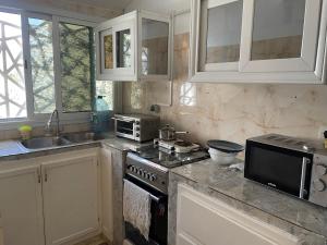 uma cozinha com armários brancos, um fogão e um lavatório em Jumeau Lo em Dakar