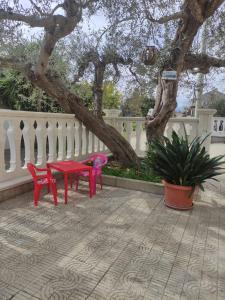 duas cadeiras vermelhas e uma mesa debaixo de uma árvore em Casa vacanze l'Ulivo em Rocca San Giovanni