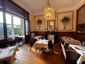 een restaurant met tafels en stoelen en een kroonluchter bij Hotel Canteklaar in De Haan