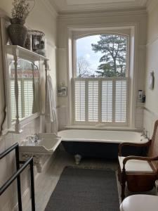 La salle de bains est pourvue d'une baignoire, d'un lavabo et d'une fenêtre. dans l'établissement Cornerstones Guest House, à Sale