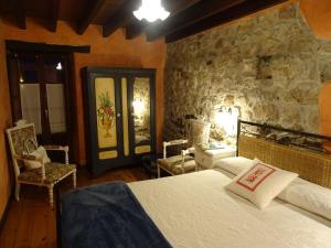 1 dormitorio con cama y pared de piedra en La Portiella del Llosu, en Pandiello
