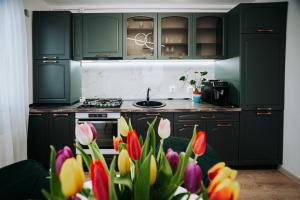a kitchen with green cabinets and a bunch of tulips at Luxury Penthouse Belvedere in Sibiu