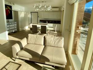 a living room with a white couch and a kitchen at EnjoyIseoLake - Corinto - wonderful Lake front apartment in Parzanica
