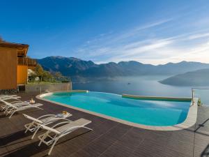 a swimming pool with chairs and a view of a lake at EnjoyIseoLake - Corinto - wonderful Lake front apartment in Parzanica