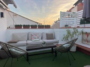 a couch on a balcony with two chairs and a table at Fantastic Penthouse Malaga Center in Málaga