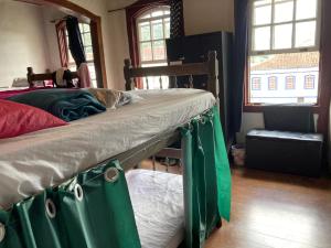 a bunk bed with green curtains on it in a bedroom at La Musica Hostel OuroPreto in Ouro Preto