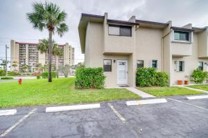 a apartment building with a palm tree and a parking lot at Fort Pierce Rental with Pool Access - Walk to Beach! in Fort Pierce