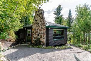 a small cabin with a stone chimney in the woods at Entire cottage in Algonquin Highlands Canada in Algonquin Highlands