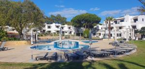 a swimming pool with lounge chairs in front of a building at P209 Balaia Golf Village in Albufeira