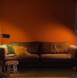 een bank in een kamer met een oranje muur bij Zuid Limburg Huisje Josefien in Simpelveld