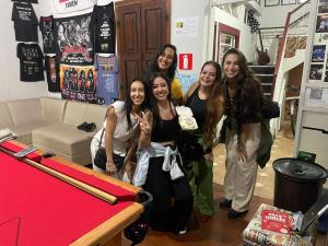 a group of girls standing next to a table with a baseball bat at La Musica Hostel OuroPreto in Ouro Preto
