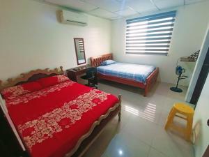Schlafzimmer mit einer roten Bettdecke und einem Bett in der Unterkunft Suite Dpto 3dorms 6 camas 1-9personas seguridad24h piscina in Guayaquil