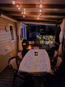 porche con mesa, sillas y sofá en Assist' Mobil Home 77 - Mobil home 3 chambres 2 salles de bain au calme en Onzain