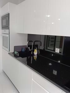 a white kitchen with a black counter top at Apartament Zielony Zakątek Wrocław in Wrocław