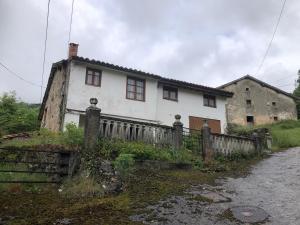 ein altes weißes Haus mit einem Zaun davor in der Unterkunft Alojamientos Casa Luisa in Puertas