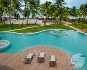 une grande piscine avec chaises et palmiers dans l'établissement Morada de Charme Milagres, à São Miguel dos Milagres